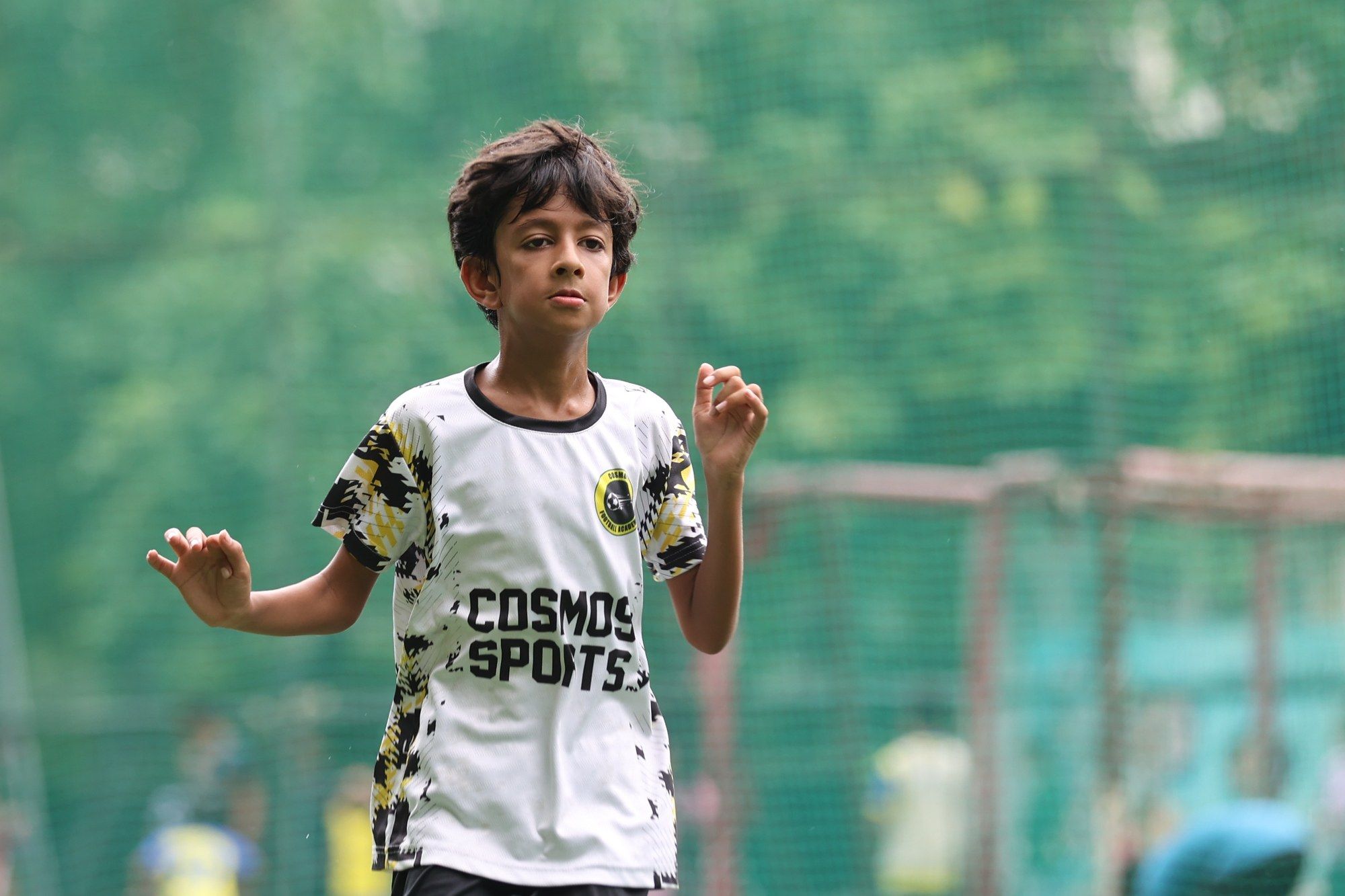 A player in the white Cosmos kit with arms out