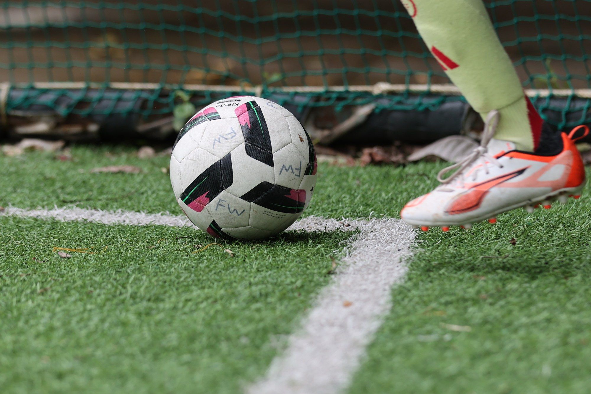 The ball on the corner line with a boot behind it