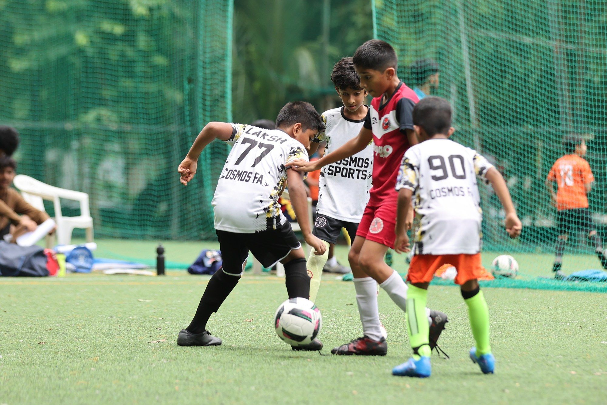 Young players crowding the ball in front of goal