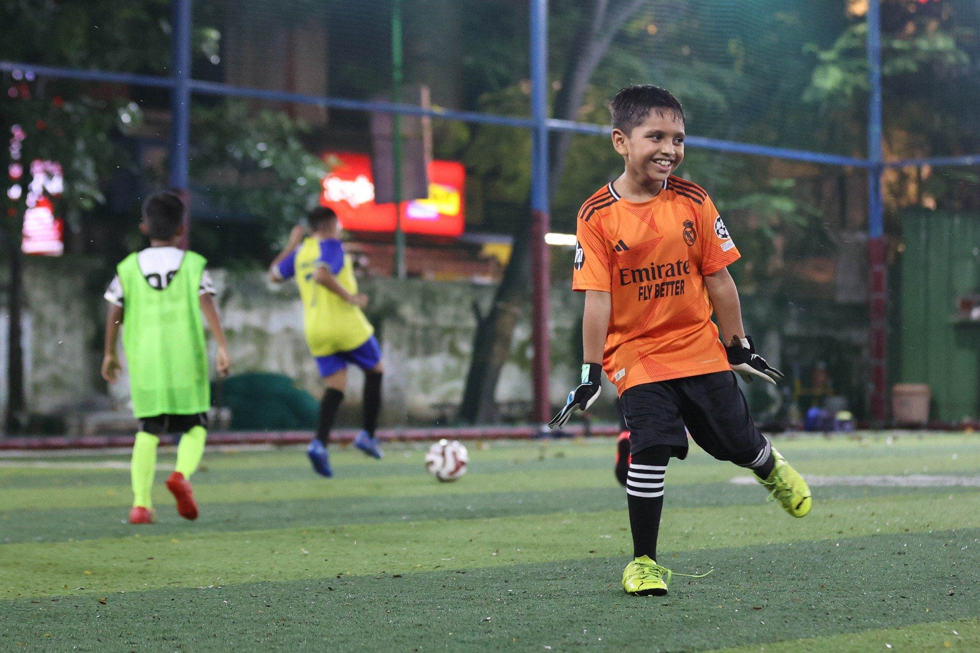 A player in an orange bib laughing during training