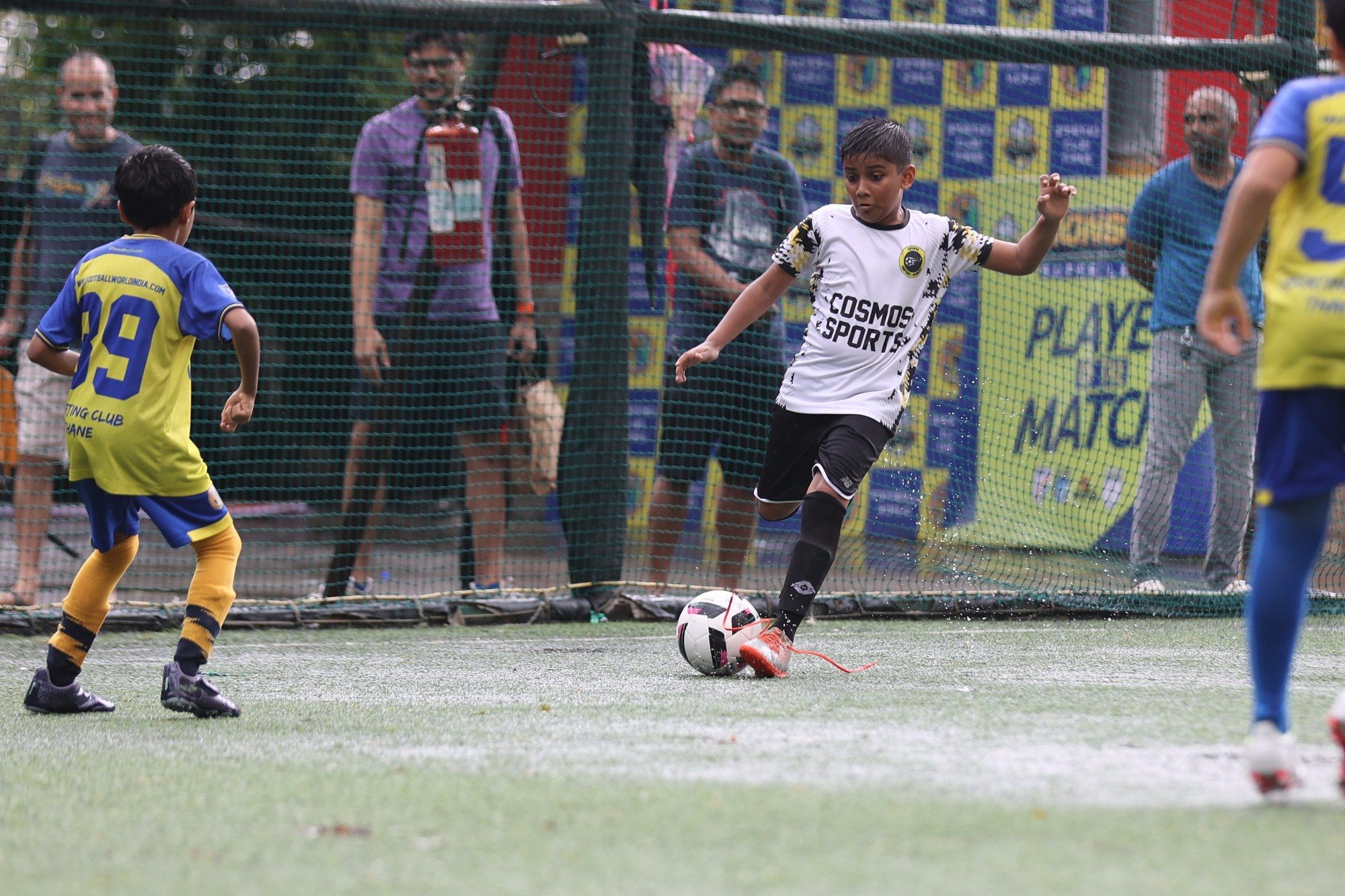 A player dribbling in front of the Player of the Match board