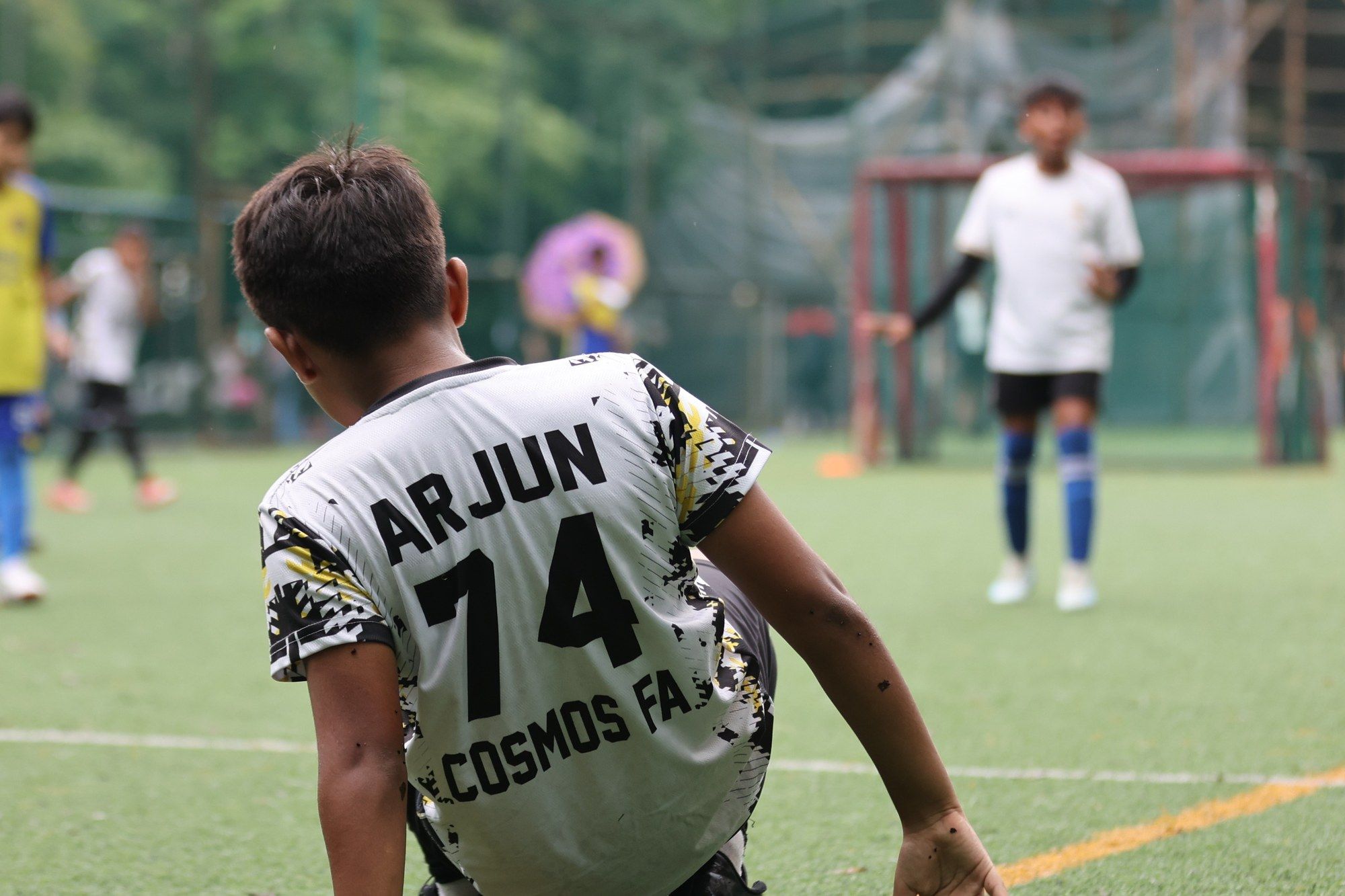 A player with Arjun 74 on his shirt, seen from behind