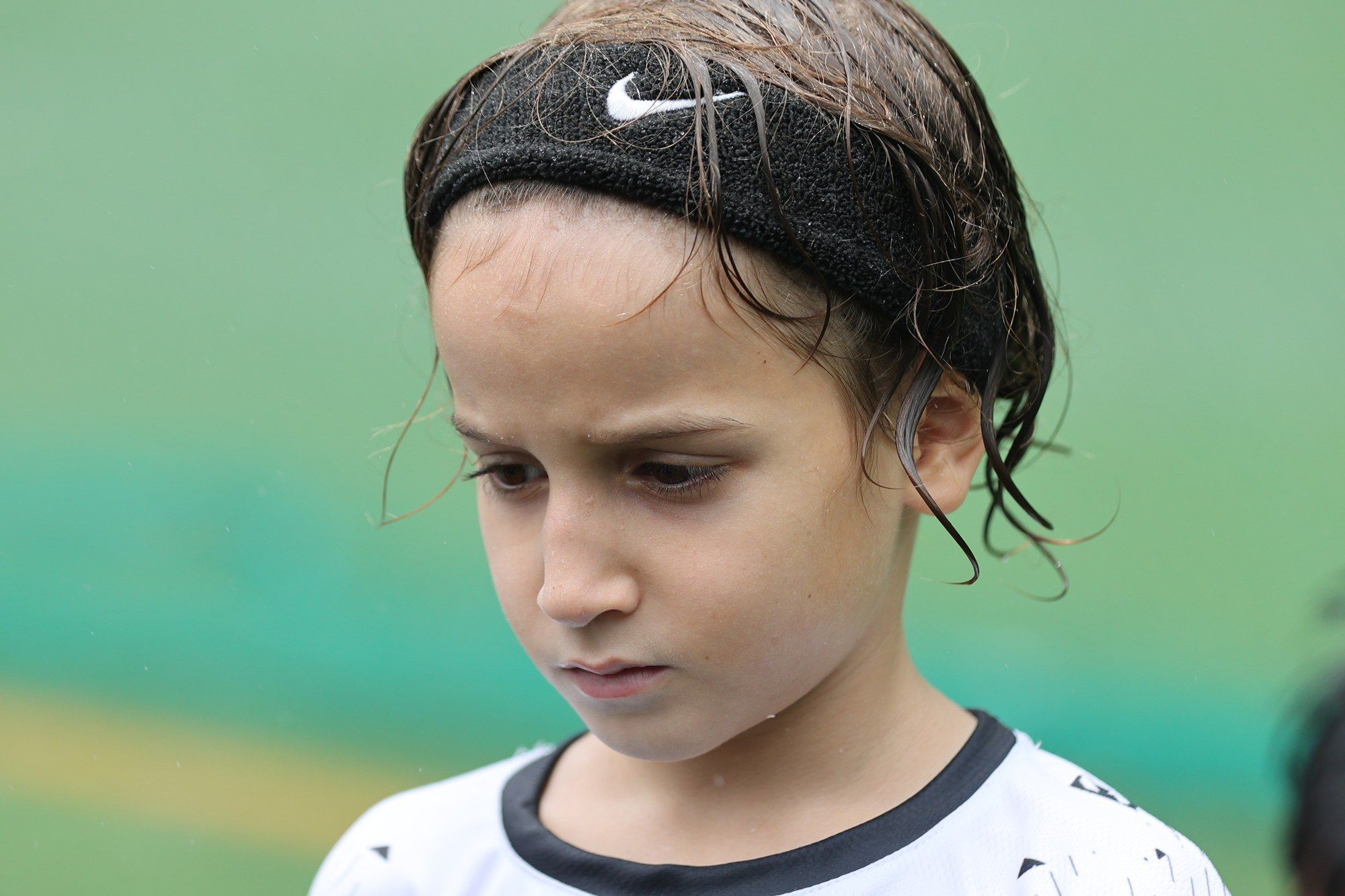 A player with a headband and wet hair, looking down