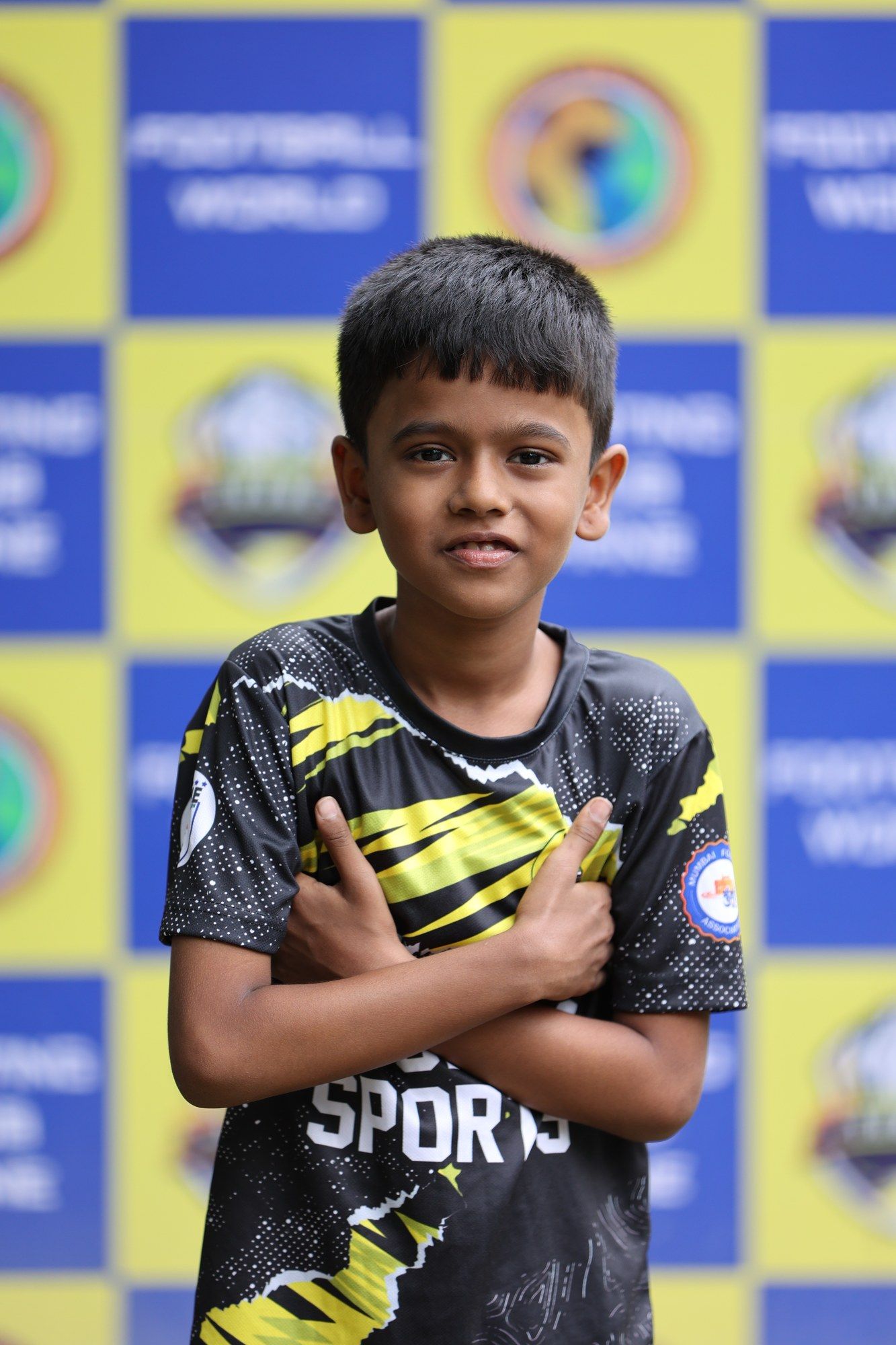 A young player in the black and yellow Cosmos kit, arms folded