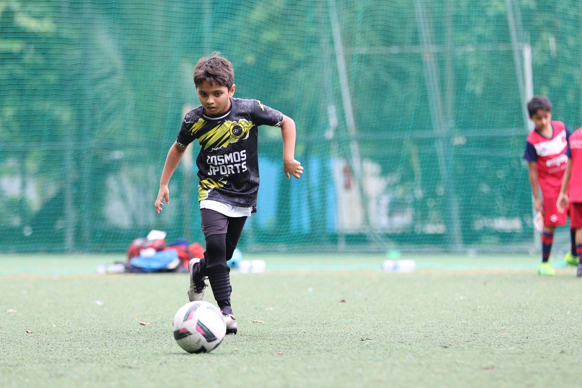 A player in the black and yellow kit dribbling